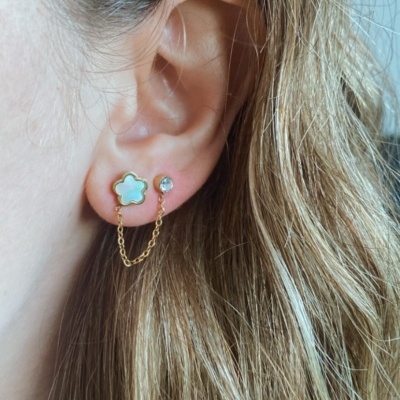 Brincos com corrente dourada e motivos flor e pedra brilhante na orelha