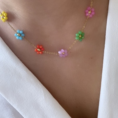 Colar com pequenas flores coloridas e corrente dourada sobre roupa branca