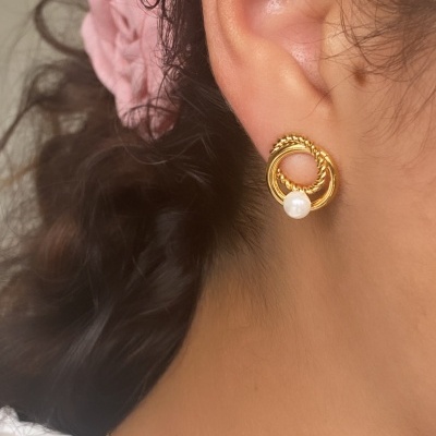 Brinco dourado circular com pérola pendurada na orelha