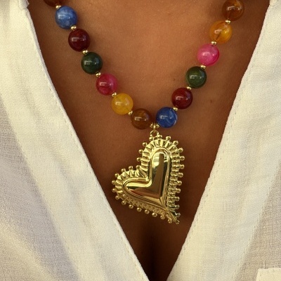 Colar colorido com pendente dourado em forma de coração sobre camisa branca