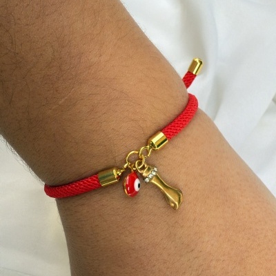 Pulseira vermelha com pingentes dourado e olho turco num pulso