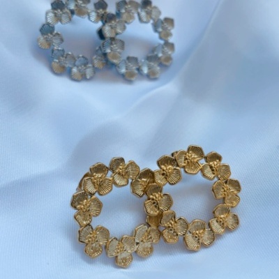 Brincos redondos de flores dourados e prateados sobre tecido branco