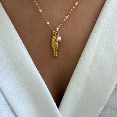 Colar dourado com pendente de peixe e pérola em roupa branca