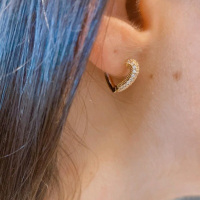 Brinco meia-lua com pedras brilhantes na orelha de uma pessoa