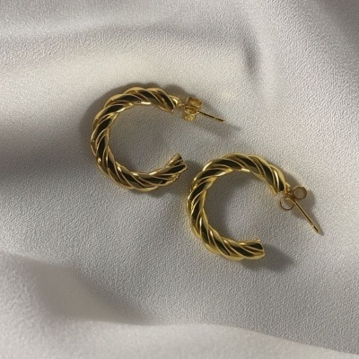 brincos dourados argola torcidos sobre tecido branco