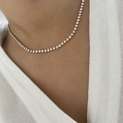 Colar riviere prata com pedras brilhantes no pescoço de pessoa com camisa branca