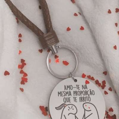 Porta-chaves com alça castanha, pendente redondo branco com texto e desenho, sobre fundo branco com confetis em forma de corações vermelhos