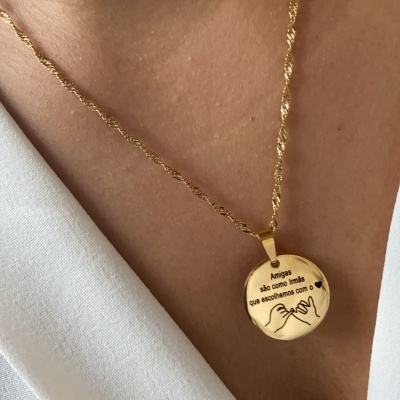 Colar dourado com pendente gravado usado no pescoço