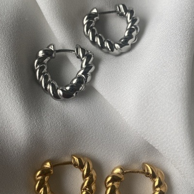 Conjunto de brincos de argola dourados e prateados com textura torcida sobre tecido branco