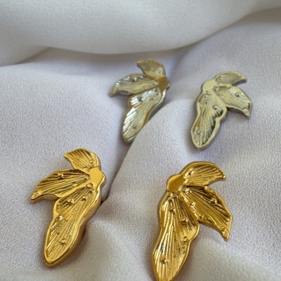 brincos em forma de folha dourados e prateados sobre tecido branco