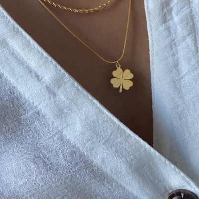Colar duplo dourado com pendente de trevo em blusa branca