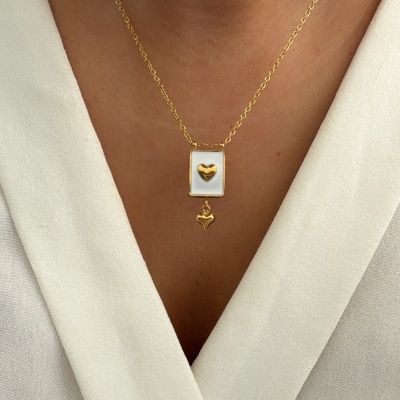 Colar dourado com pendentes de corações sobre roupa branca