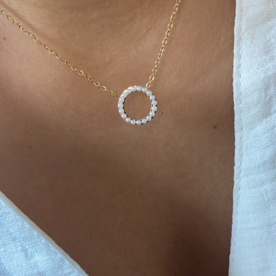 Colar com pendente de pérolas em corrente dourada perto do pescoço