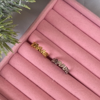 Dois anéis de folhas, dourado e prateado, numa caixa de joias rosa.