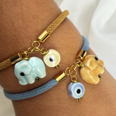 Duas pulseiras de fio trançado com pingentes de elefante em cerâmica e olhos gregos em vidro.