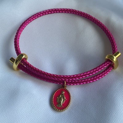 Pulseira rosa com pendente dourado sobre tecido branco