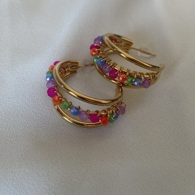 Brincos argola dourados com contas coloridas sobre tecido branco