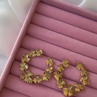 Brincos de argola dourados com design de borboletas em caixa rosa