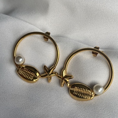 Par de brincos dourados com concha e pérola em fundo branco