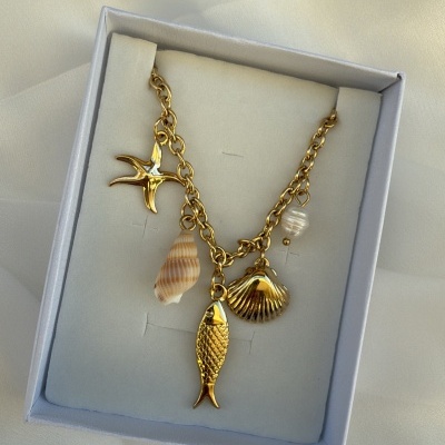 Colar dourado com pendentes marinhos numa caixa branca