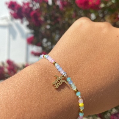 Pulseira colorida com pendente dourado em forma de abacaxi no pulso