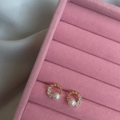 Brincos dourados com pérola e cristais numa caixa rosa de veludo