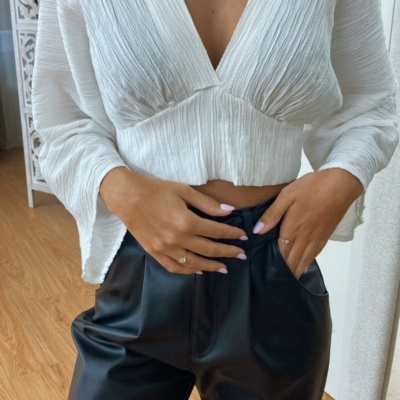 Blusa branca texturizada com calças pretas de tecido efeito pele