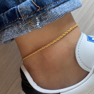 Tornozeleira dourada no tornozelo com jeans e ténis branco