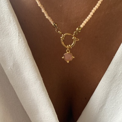 Colar rosa com pendente dourado em cruz e vestido branco