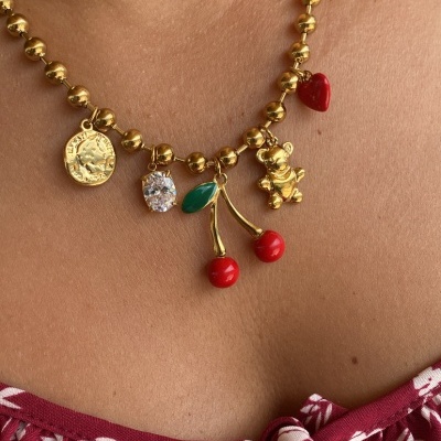 Colar dourado com pendentes variados usado junto do pescoço.