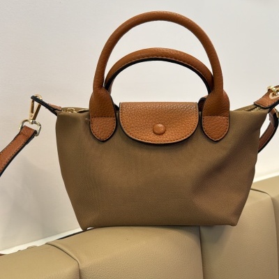 Mala pequena de mão castanha em tecido e pele sobre cadeira bege