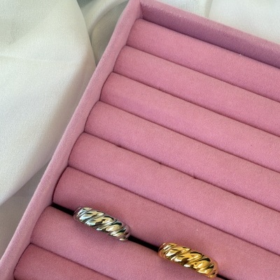 Uma caixa de veludo cor de rosa com duas argolas trançadas, uma prateada e outra dourada.