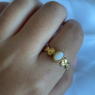 Anel dourado com pedra branca num dedo