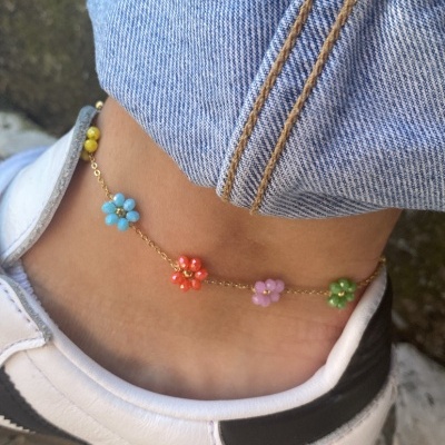 Tornozeleira colorida com flores em tornozelo junto a ténis e calça de ganga