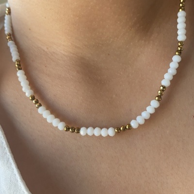 Colar com contas brancas e douradas no pescoço