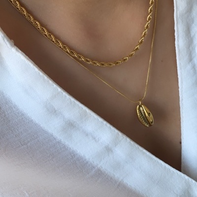 Duas colares dourados em pescoço com camisa branca