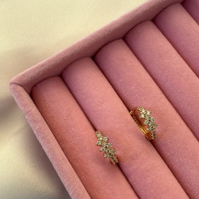 Brincos dourados com pedras brilhantes em caixa almofadada cor-de-rosa