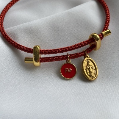 Pulseira vermelha trançada com medalhas douradas em tecido branco