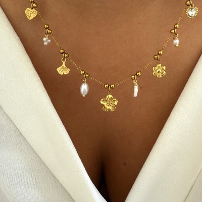 Colar dourado com pingentes de flores, corações e pérolas, em pescoço com roupa branca