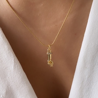 Colar dourado com pendente de mão e chave