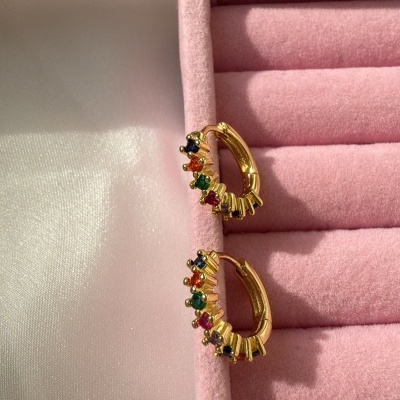 Brincos de argola dourados com pedras coloridas numa caixa de veludo rosa