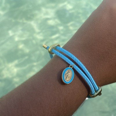 Pulseira azul com pingente dourado e fundo de água clara