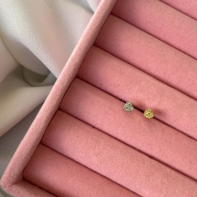Brincos em forma de coração prateado e dourado numa caixa de veludo rosa.