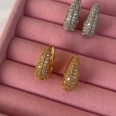 Dois pares de brincos em forma de gota com brilhantes num suporte de veludo rosa