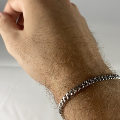 Pulseira prateada de corrente grossa no pulso de mão masculina