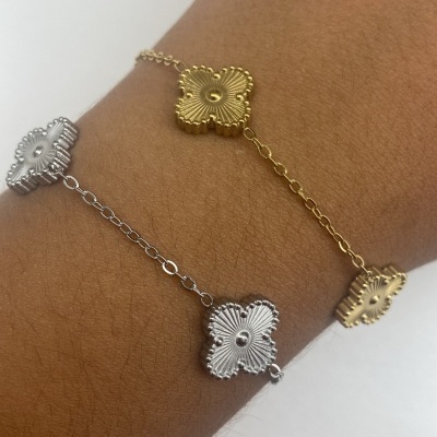 Pulseiras dourada e prateada com pendentes de flor no pulso.