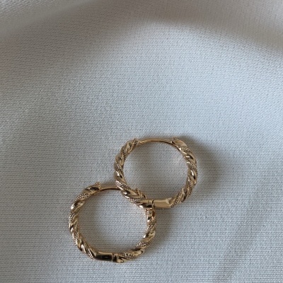 Brincos de argola dourados com textura torcida sobre fundo branco