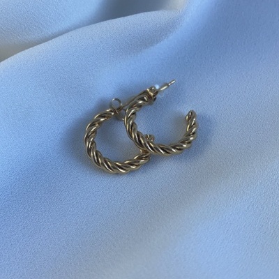 Brincos de argola dourados torcidos sobre tecido branco