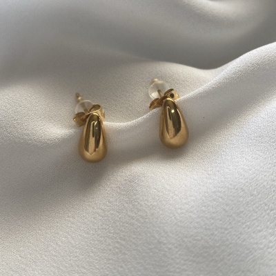 Brincos dourados pequenos sobre tecido branco