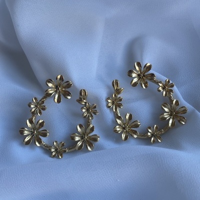 Brincos dourados em forma de flores sobre tecido branco